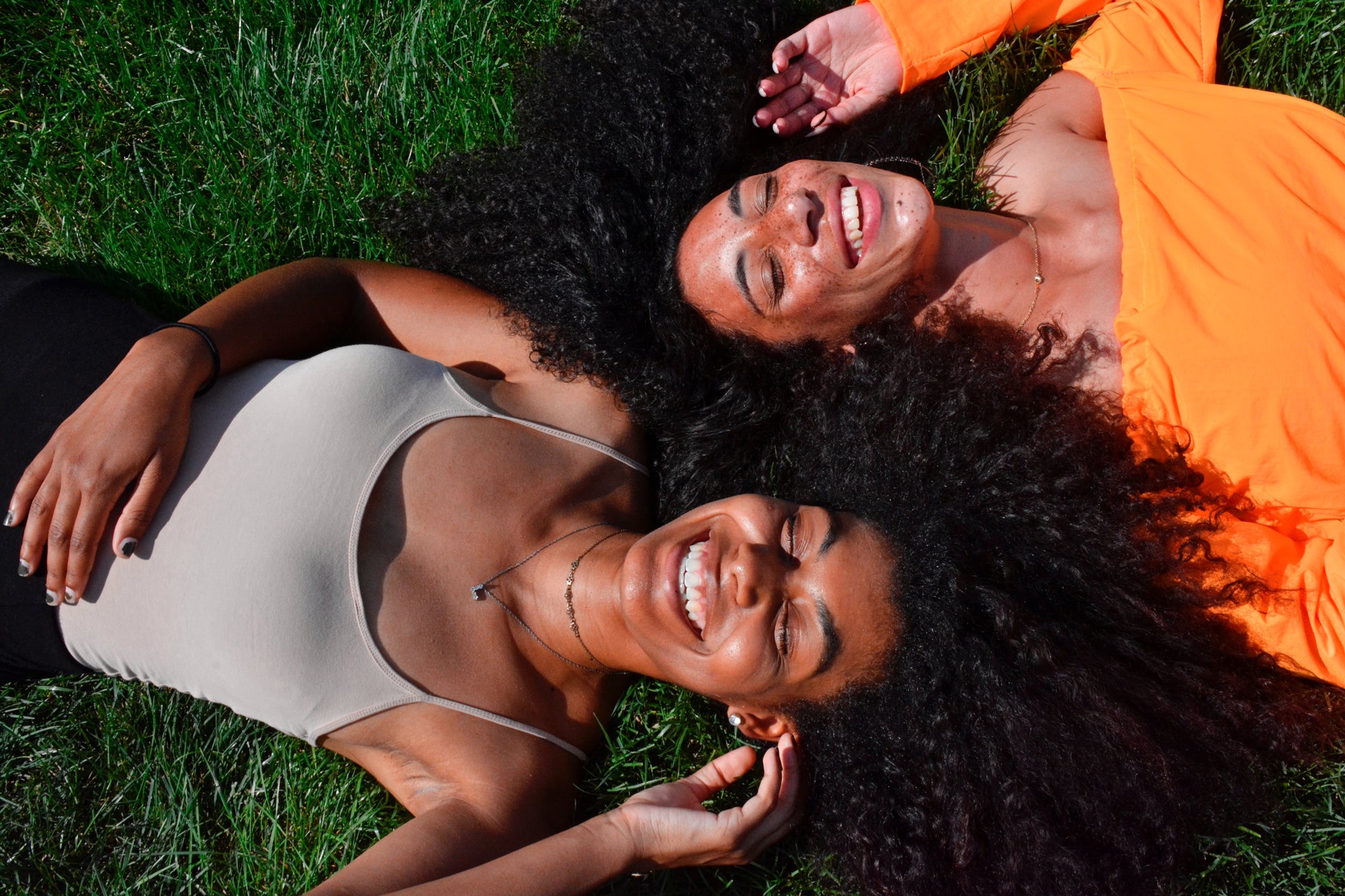 two women laughing outside on grass